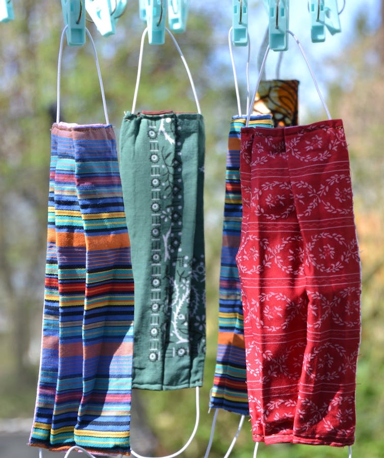 Four cloth masks hanging on a clothesline.